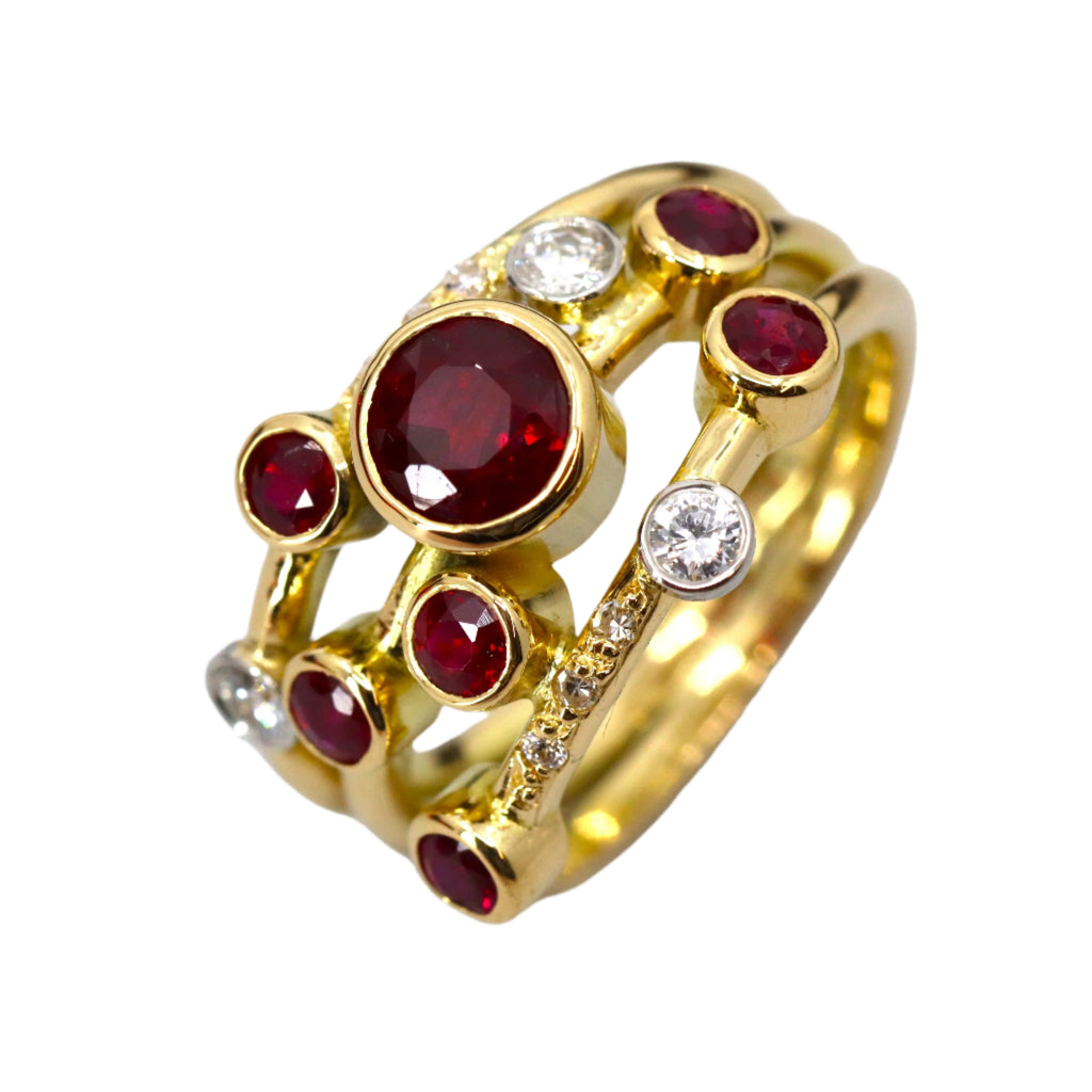 Gold ring split into 3 bands with different sizes of round red and white gemstones set in circles of gold on the bands